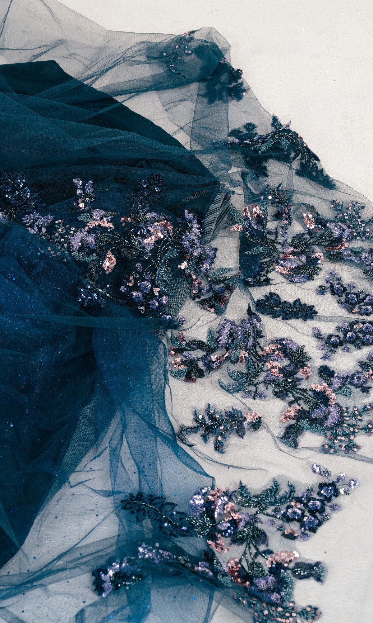 Dark blue sheer fabric with purple, pink, and silver sequin floral embroidery—ideal for the Quinceanera Dress 8440JQ by Cinderella Couture or a dreamy ball gown, elegantly displayed on a light surface.